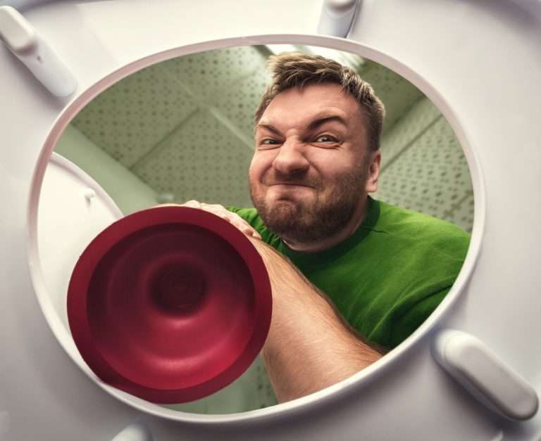 plumber with plunger looking into toilet angrily