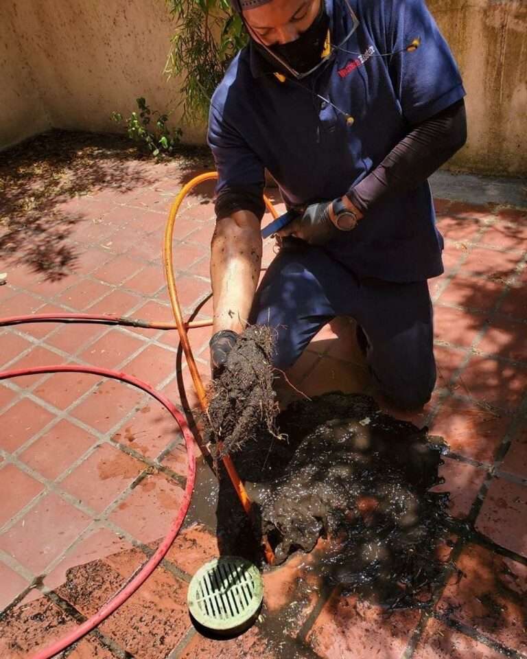 Clearing an area drain before the rainy season starts.