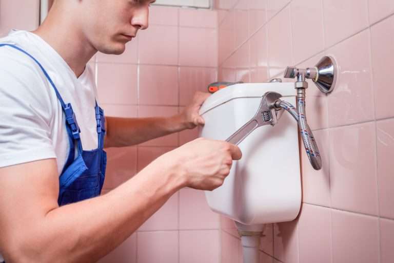 plumber fixing a toilet tank