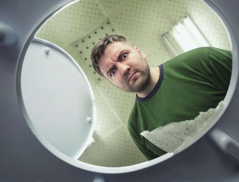 man staring into a toilet bowl, confused, clogged toilet
