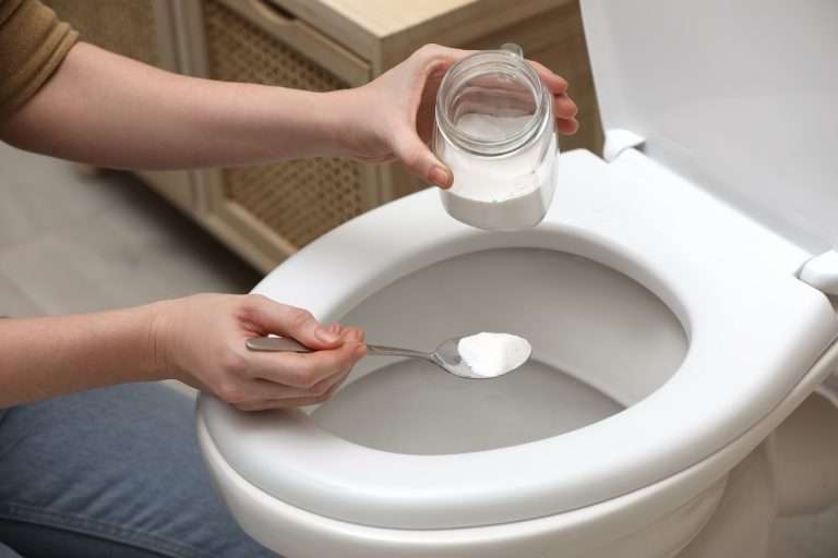 woman using baking soda to clean toilet