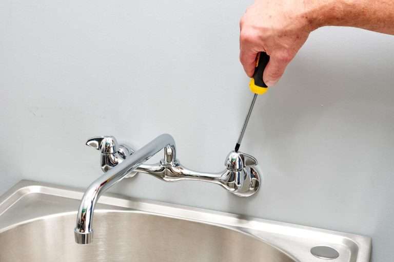 a person fixing a leaky faucet in the bathroom sink