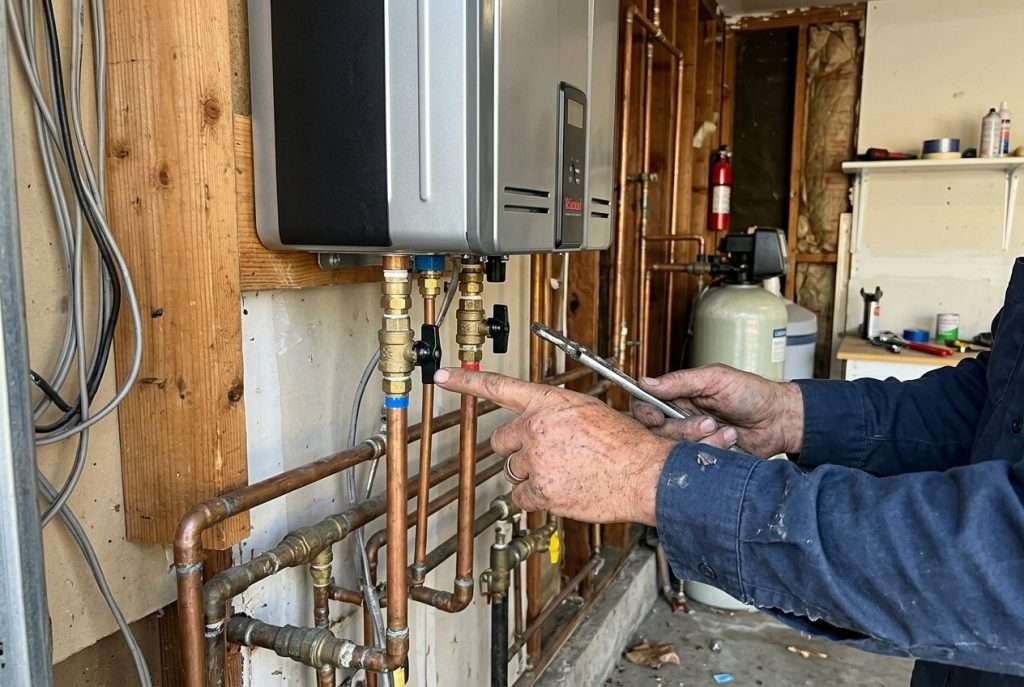 Hands adjusting isolation valves on a tankless water heater