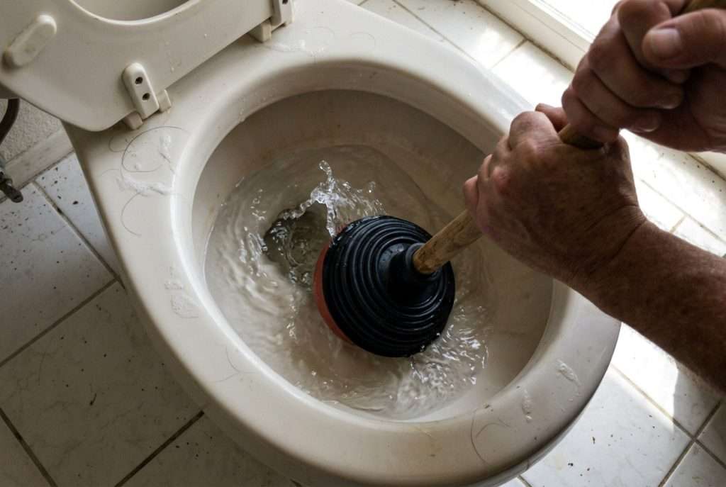 Using a flange plunger on a clogged residential toilet