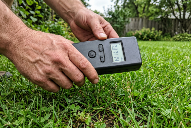 Plumber using a handheld pipe locator device to trace an underground water line