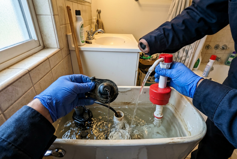 Plumber replacing a toilet flapper and fill valve inside an open toilet tank